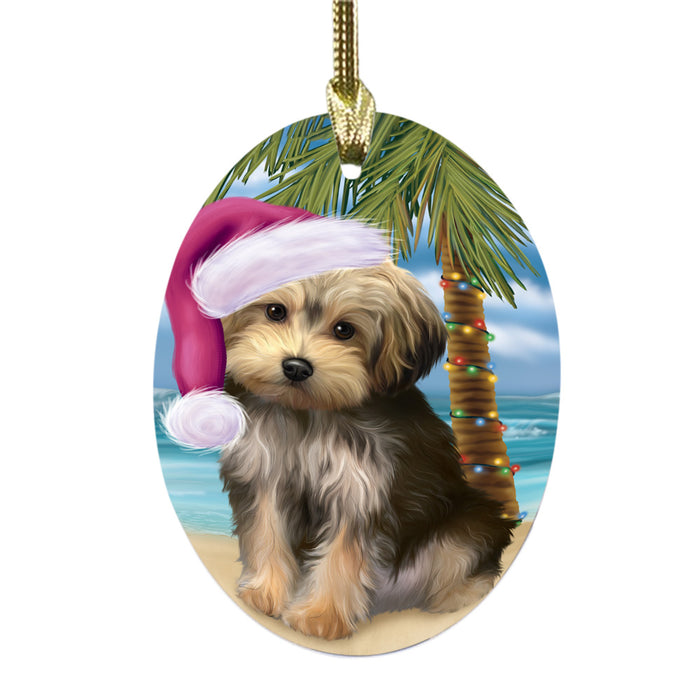 Summertime Happy Holidays Christmas Yorkipoo Dog on Tropical Island Beach Oval Glass Christmas Ornament OGOR49413
